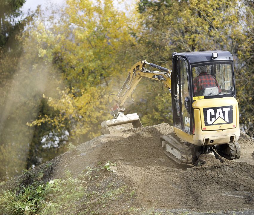 Bagger auf Erdhügel beim Streckenbau.